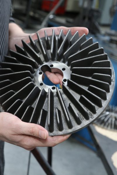Bryon holds up a tension brake disc, which is used in the manufacturing process to help regulate tension.