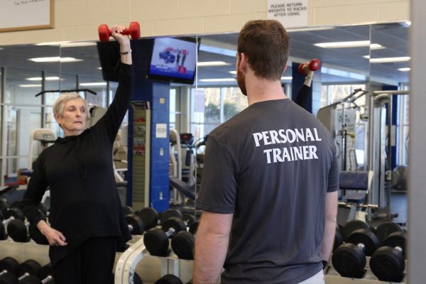 Tommy Dahlborg ’18 trains clients at the Alfond Center, including Professor Mary Lynn Engel, who works on her triceps.