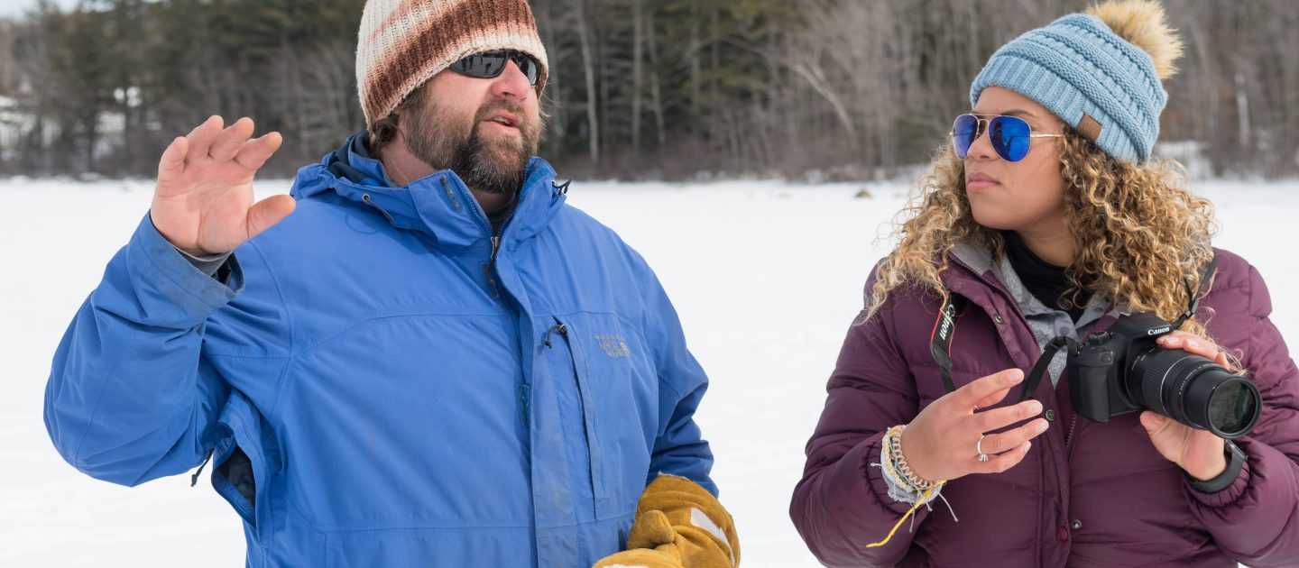 Art professor Scott Fuller instructs a student in digital photography outside on a frozen Sebago Lake